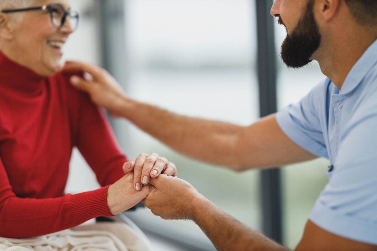 A caregiver kneeling to speak with a patient at eye level