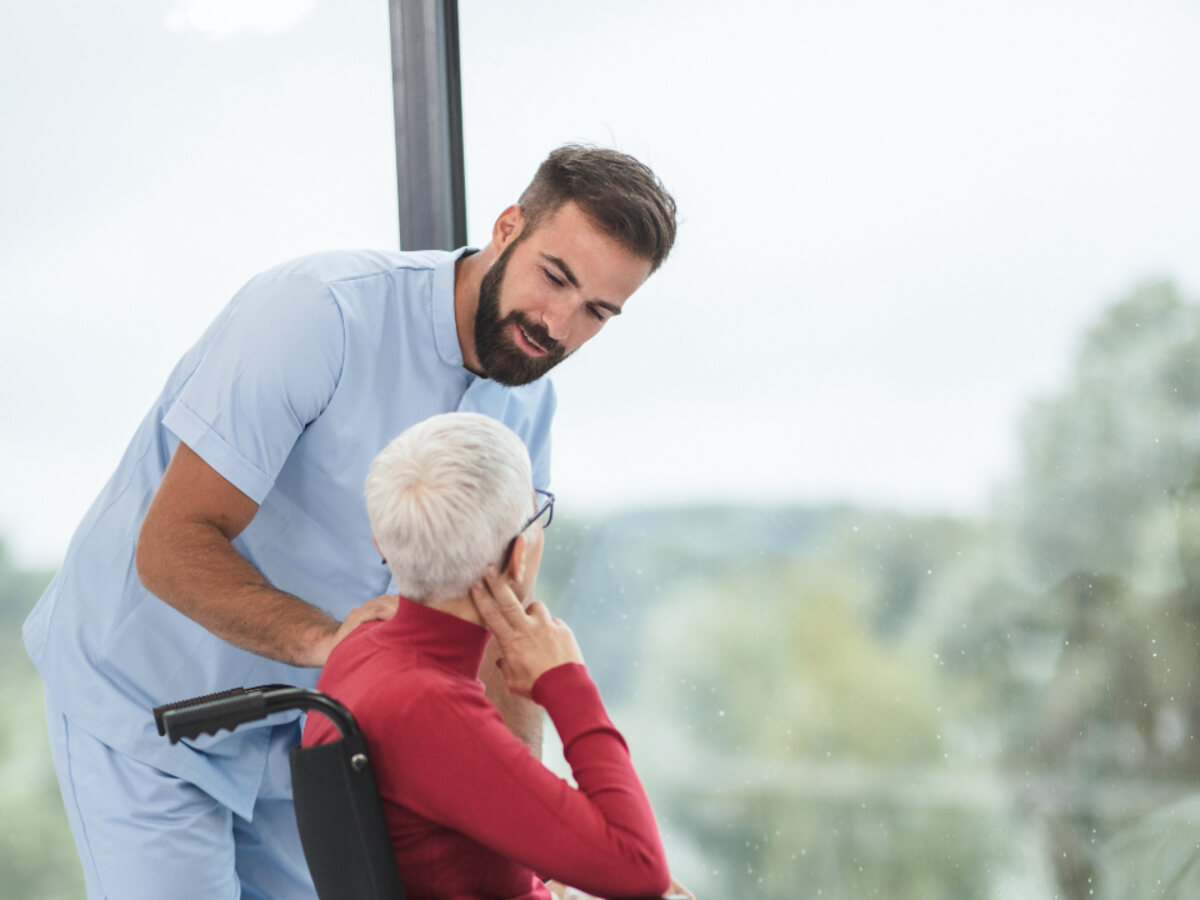 A caregiver helping a patient settle comfortably into a wheelchair