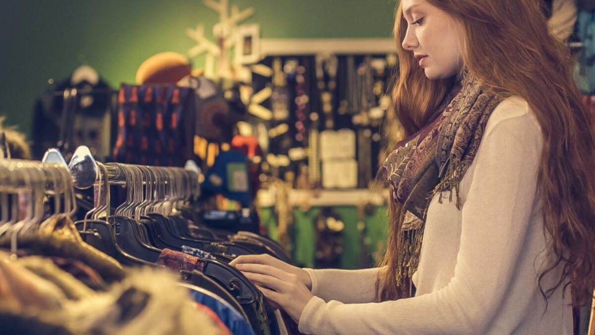 A shopper browsing racks of clothing in the thrift store